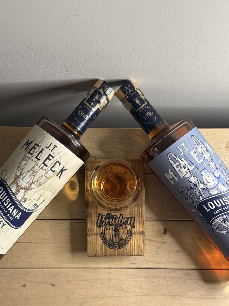 JT Meleck 100% rice whiskey 96 proof bottle and 118 proof bottles with heads angled towards each other and glencairn in the middle