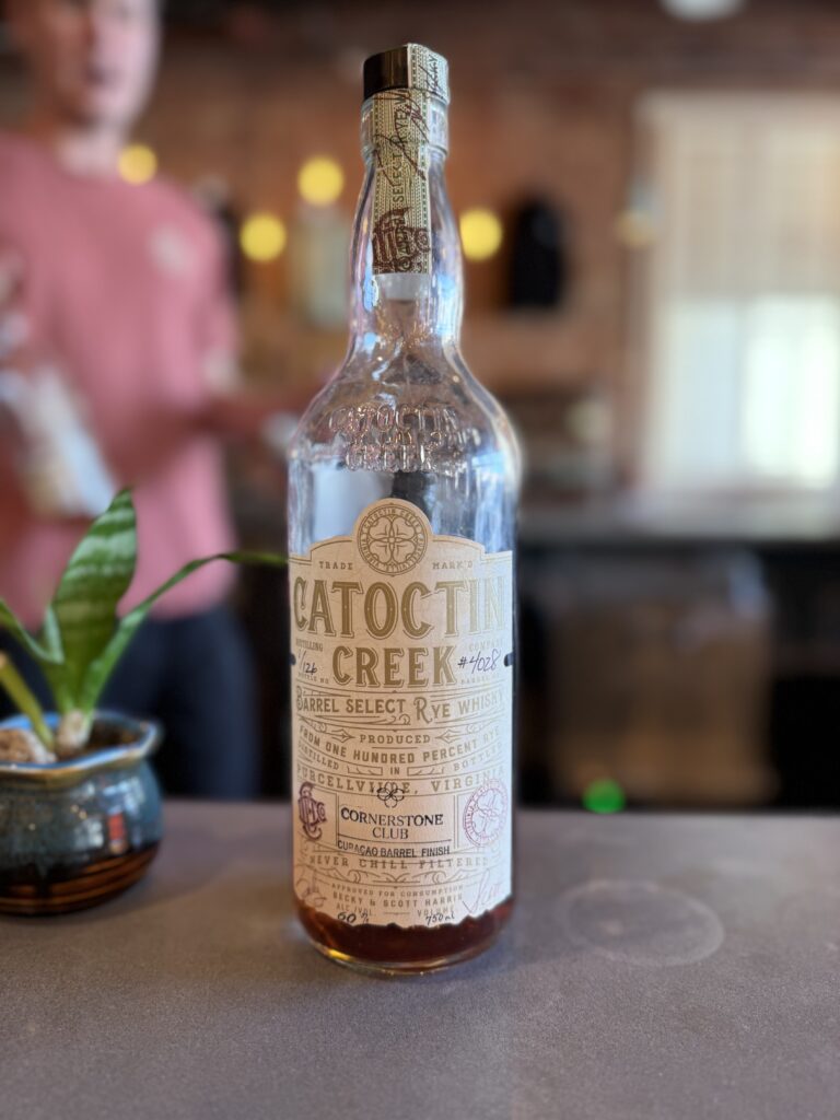Catoctin Creek Cornerstone Club Curacao Finished Rye sitting on bar, bartender walking behind