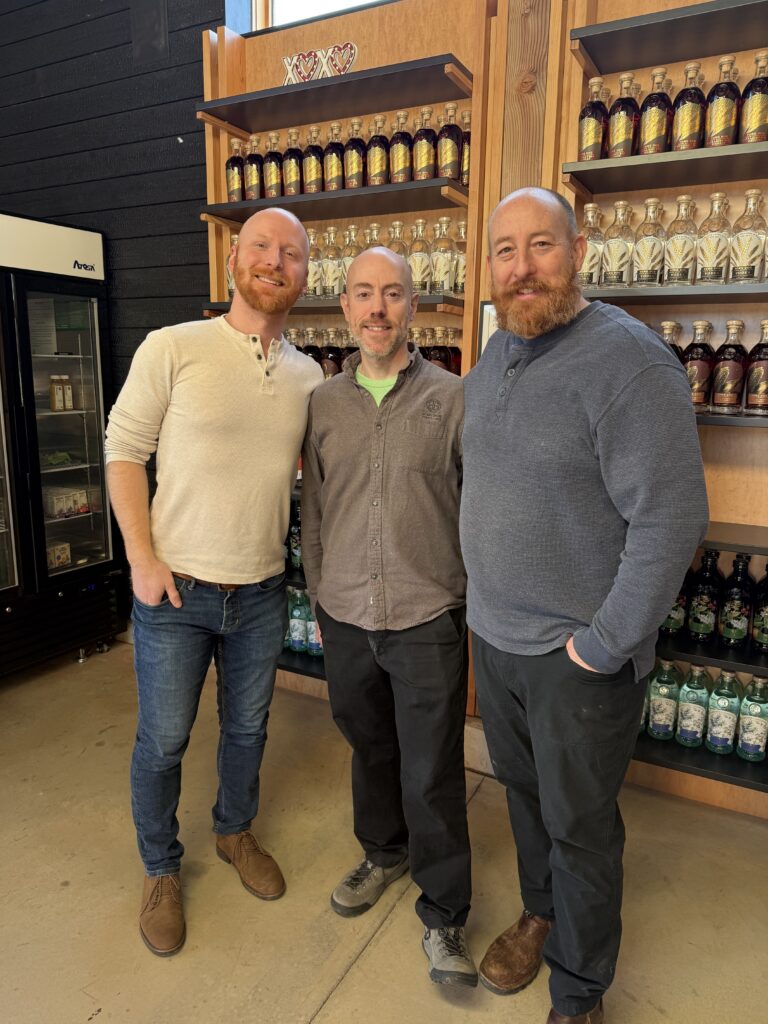 (Left to Right) E.S. Pope, Owner David Harris, and Head Distiller Kristian Naslund in front of gift shelves