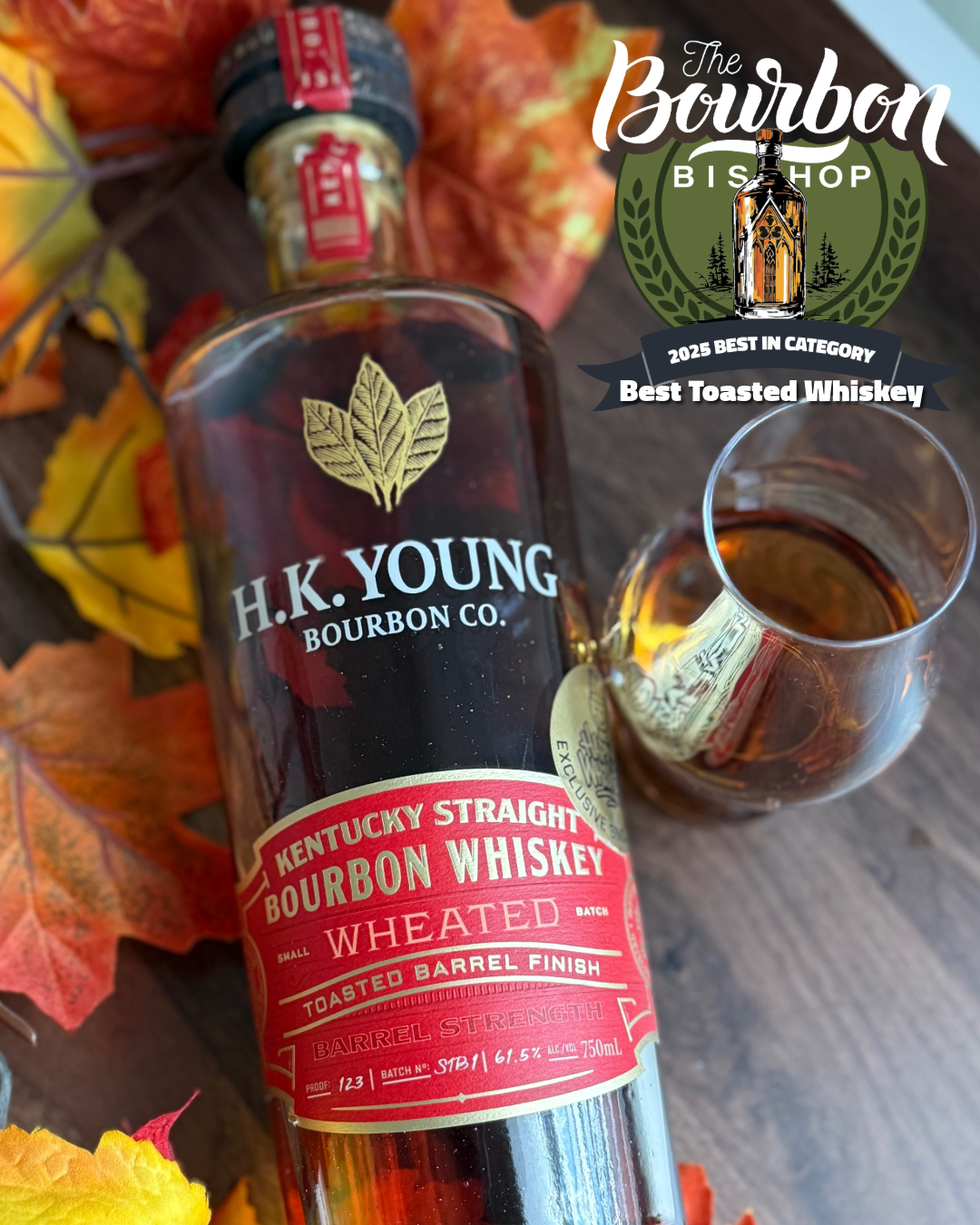 H.K. Young Toasted Wheated Bourbon "Happy Whisk3y" Single Barrel Pick lying beside orange and red fall leaves with full glass and The Bourbon Bishop Logo and header that says "Best Toasted Whiskey of 2025"