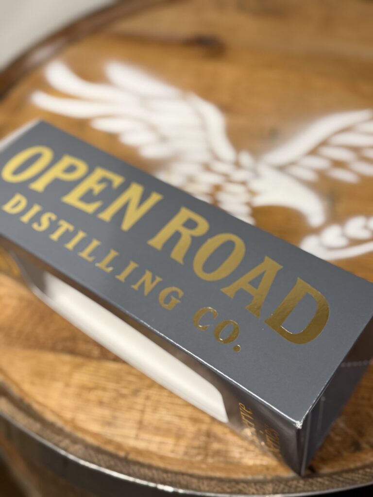 Open Road Reserve Series box lying beside Open Road logo on whiskey barrel head