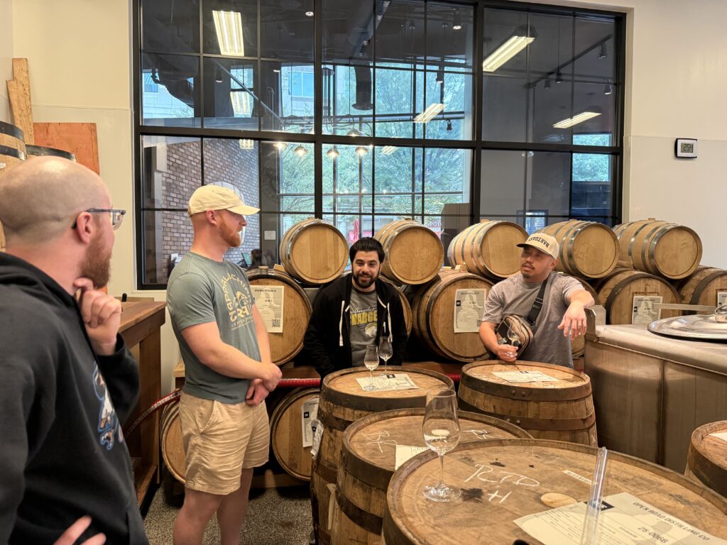 Mike McElroy, E.S. Pope and friends in Open Road distilling room talking in front of whiskey barrels