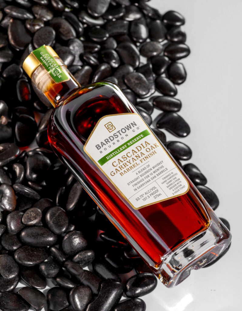 Bardstown Bourbon Company "Cascadia" Garryana Oak Finished Bourbon lying against black stones (Photo Credit: Lofted Spirits)