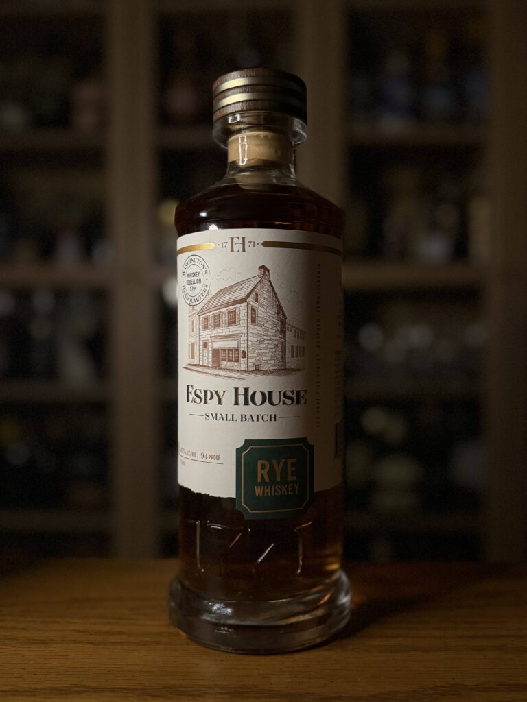 Espy House Rye sitting on desk in front of whiskey collection.