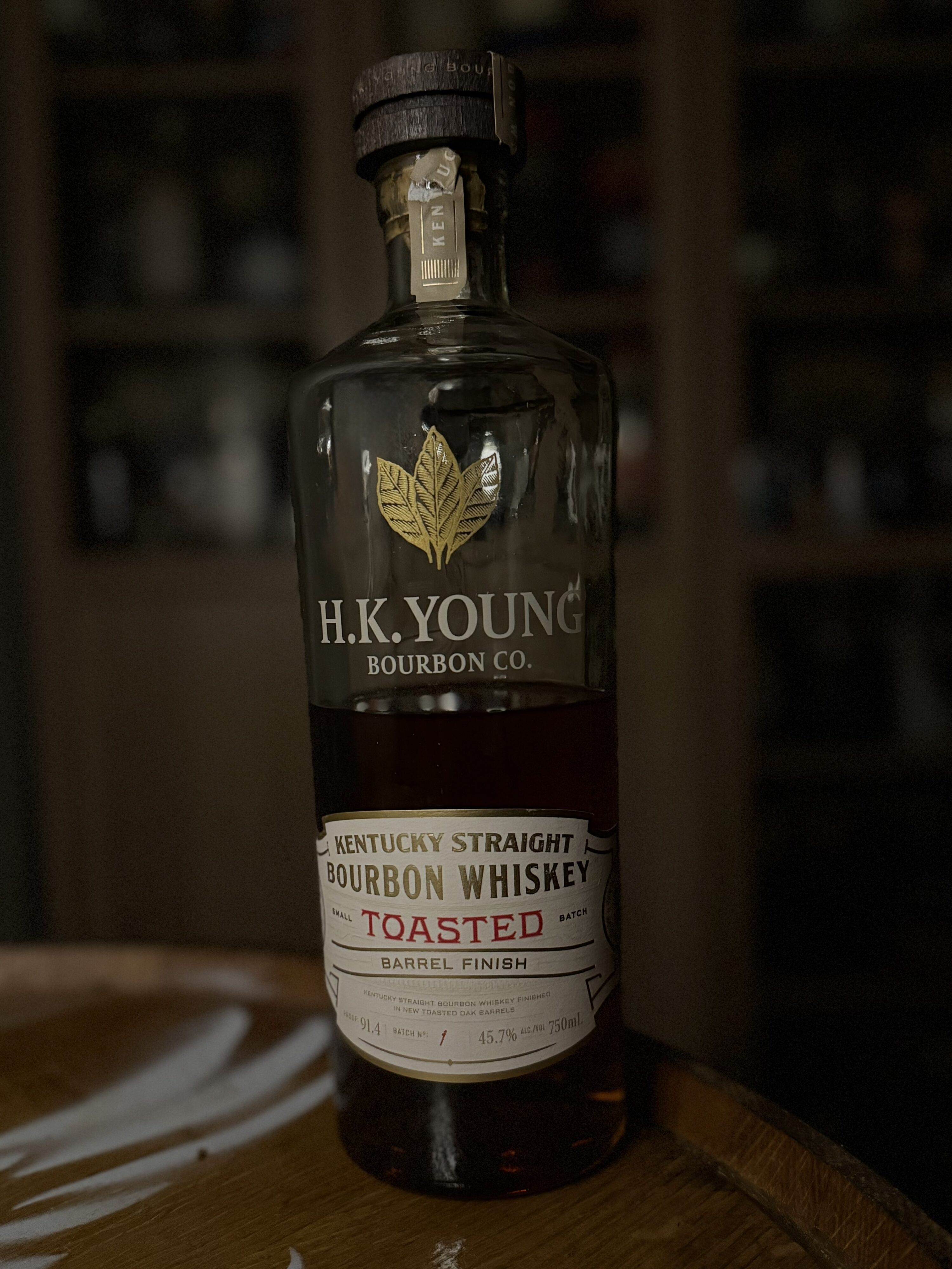 H.K. Young Toasted Small Batch Bourbon standing on whiskey barrel in front of collection