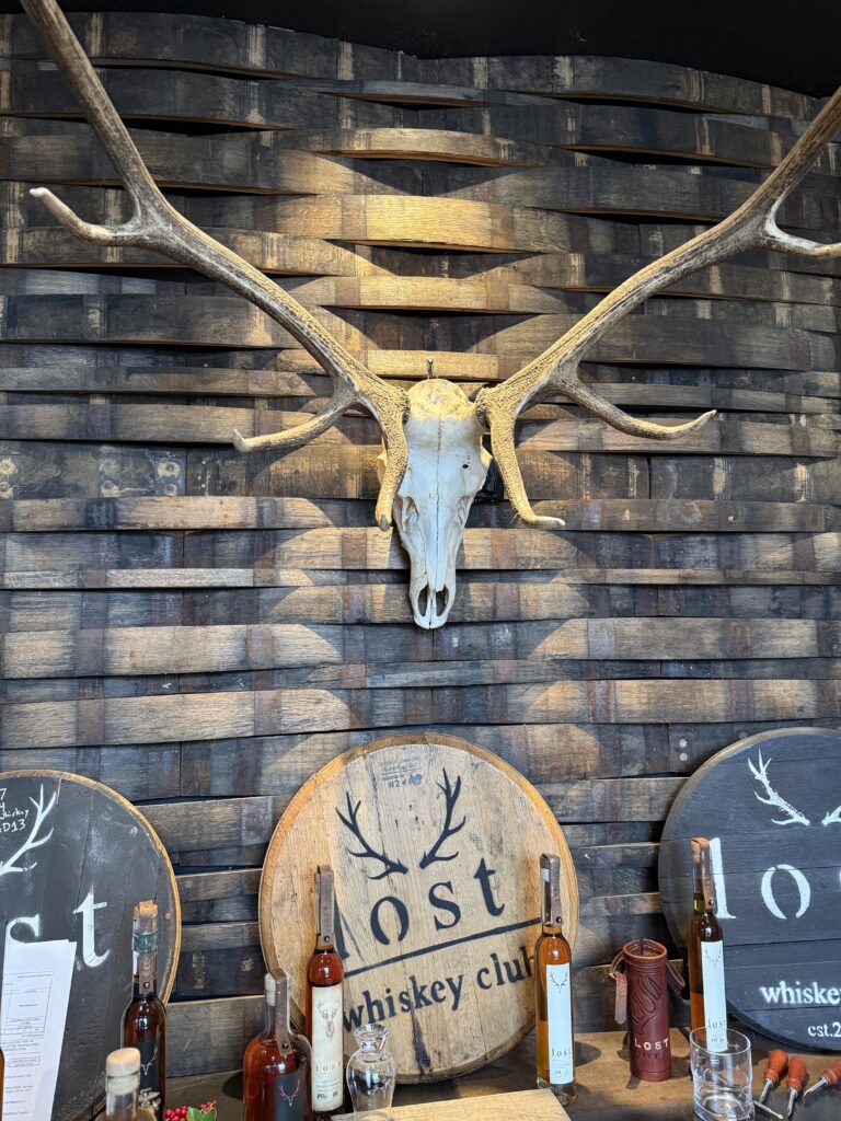 Lost Whiskey Club tasting room with antlers, barrel heads, and bottles