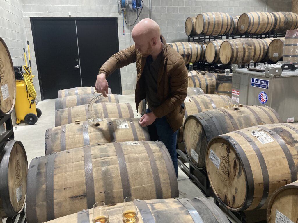 E.S. Pope pouring rye whiskey straight from the barrel using thief