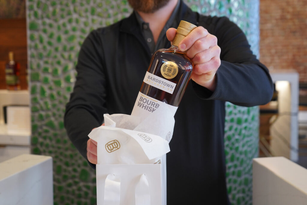 Bardstown Bourbon Company bottle with NFC tag sticker is placed into branded gift bag