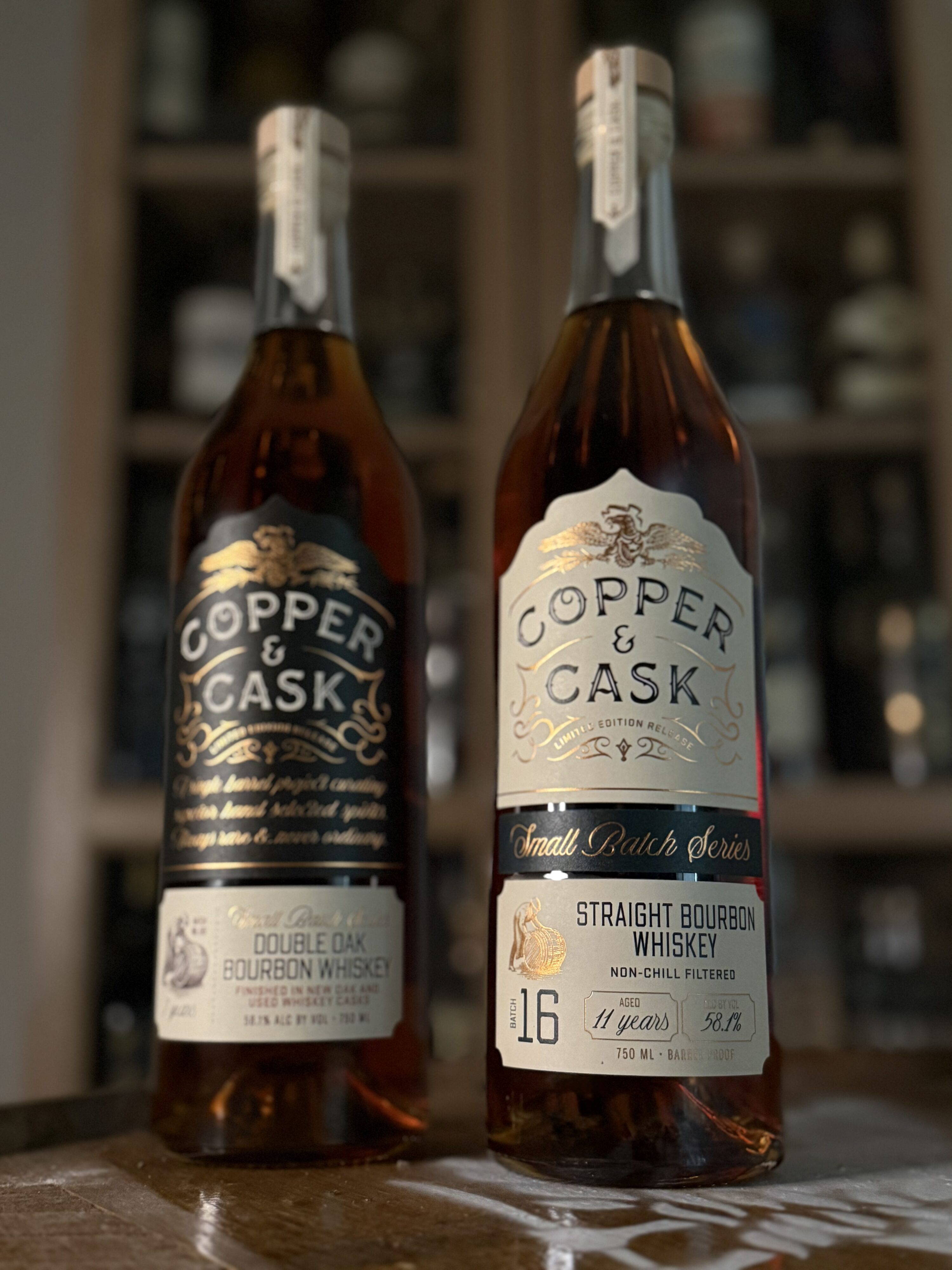 Copper & Cask Small Batch Series 07 & 16 side by side in front of whiskey collection