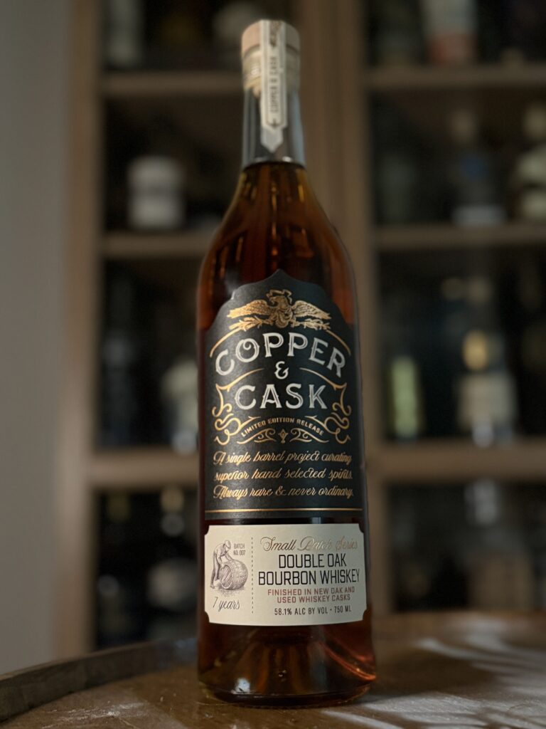 Copper & Cask Double Oaked Small Batch Series 07 in front of whiskey collection
