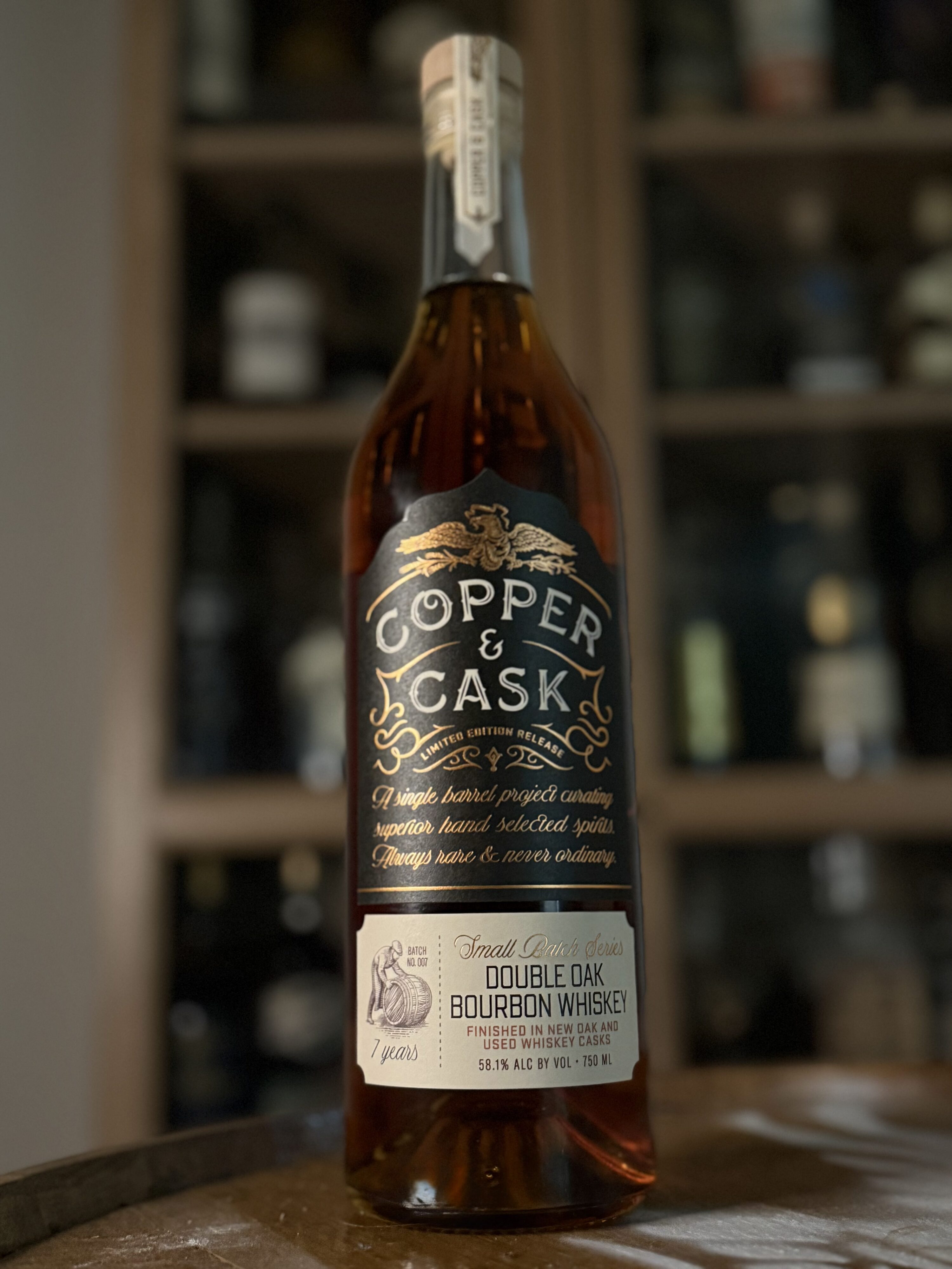Copper & Cask Double Oaked Small Batch Series 07 in front of whiskey collection