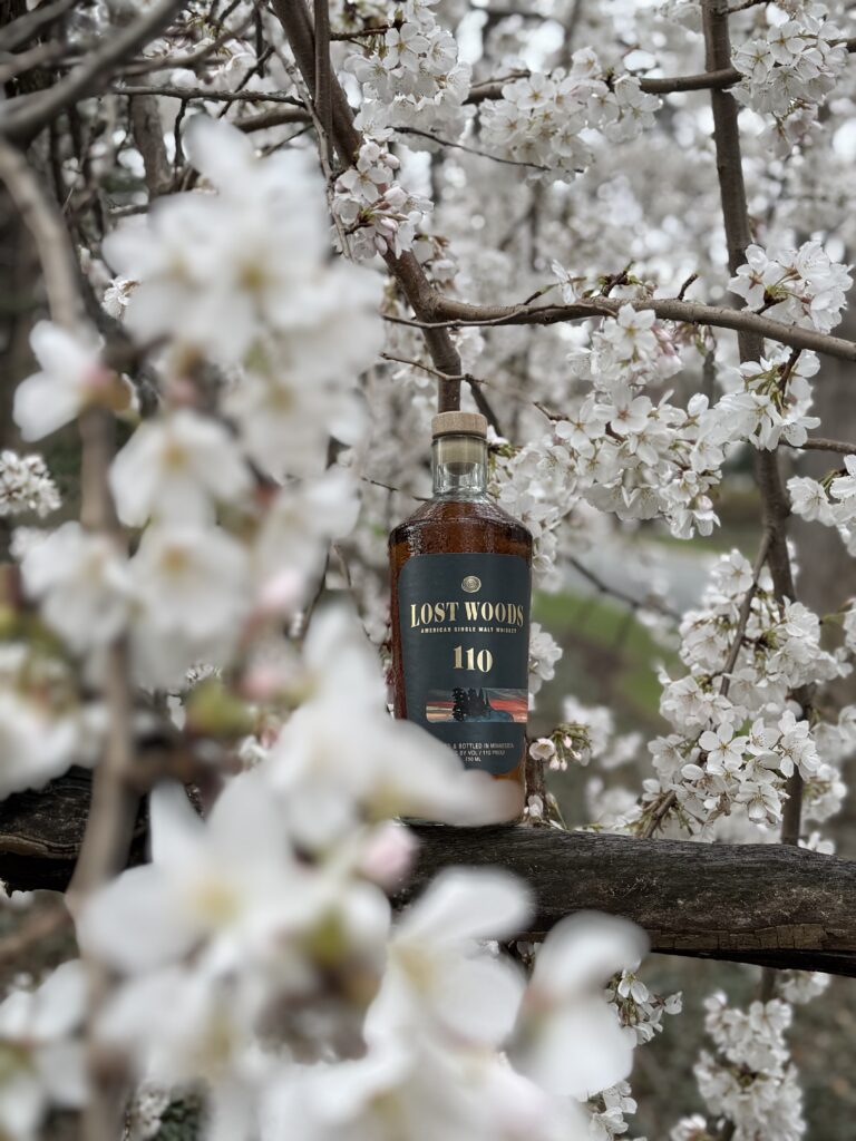 Lost Woods 110 Proof (Cask Strength) seen through obscuring white cherry blossoms