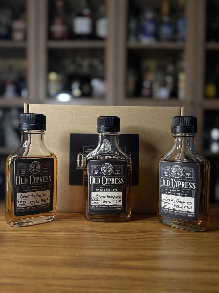 Old Cypress samples on desk in front of whiskey collection