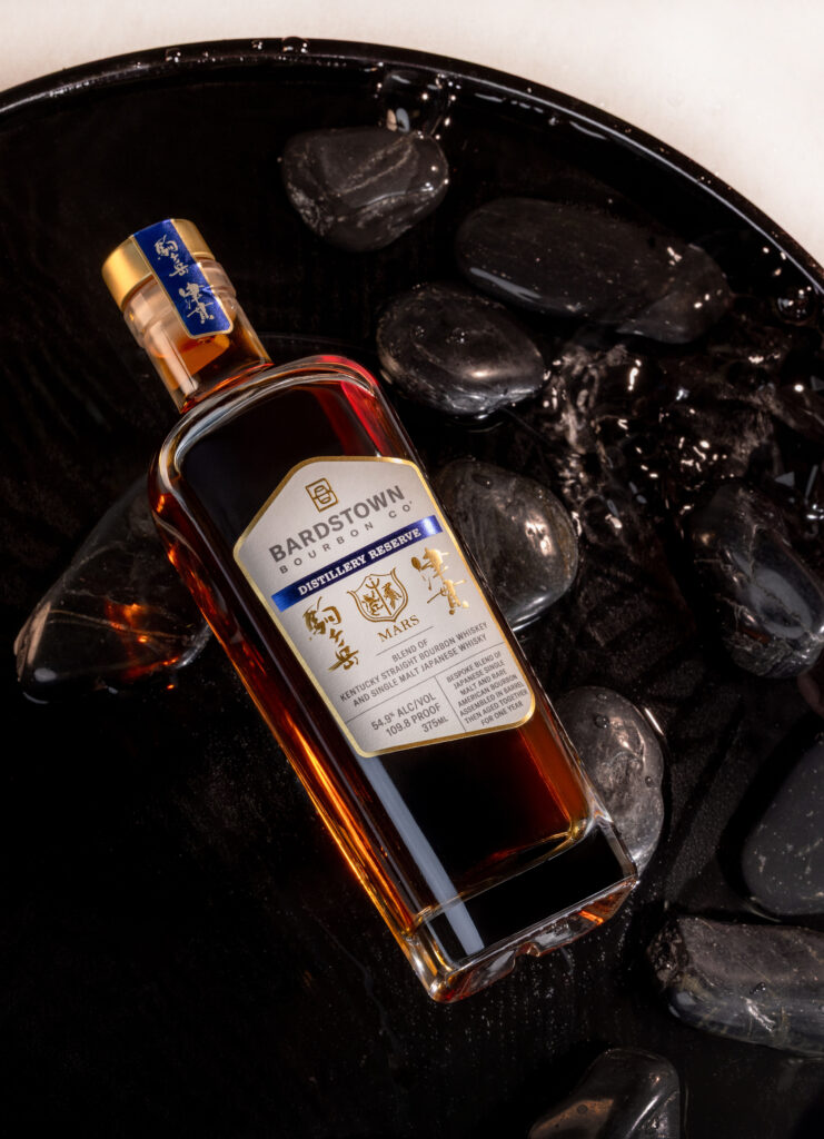 Bardstown Bourbon Company's Distillery Reserve Mars Blendd lying in still water and dark stones