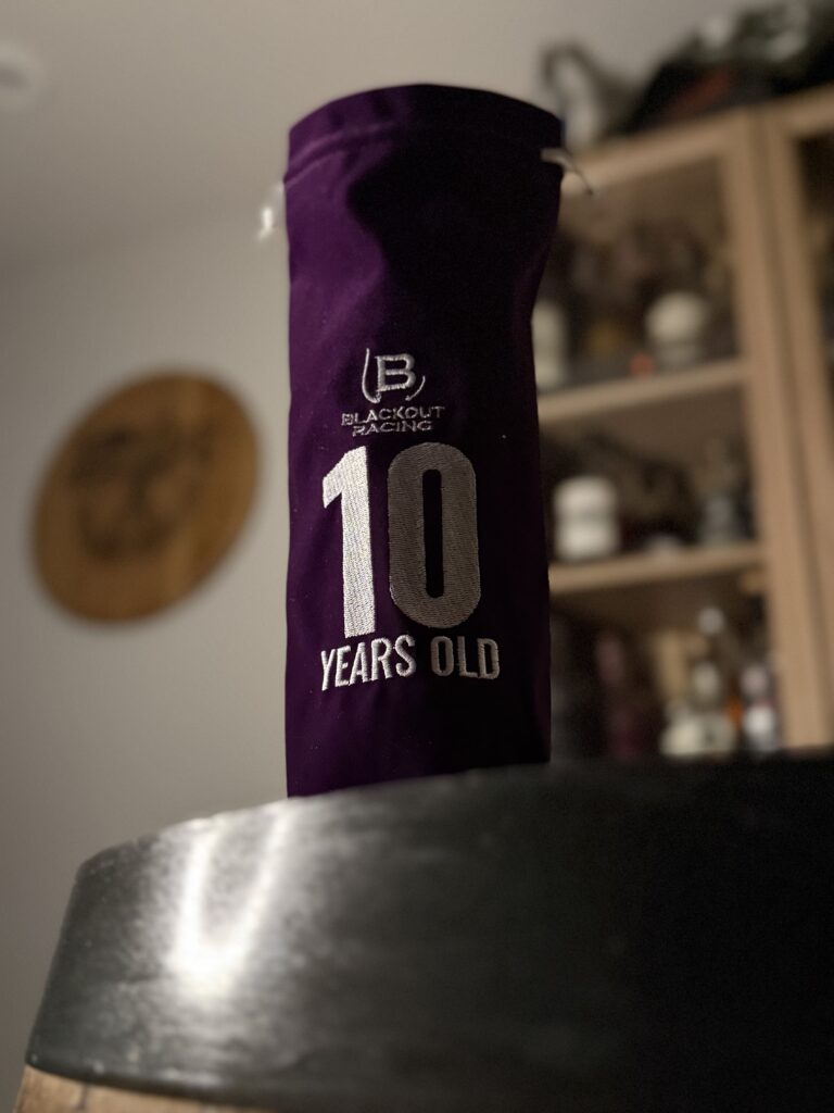 Blackout 10 Year Cask Strength Single Barrel Rye in premium, purple age stamped bag standing on barrel