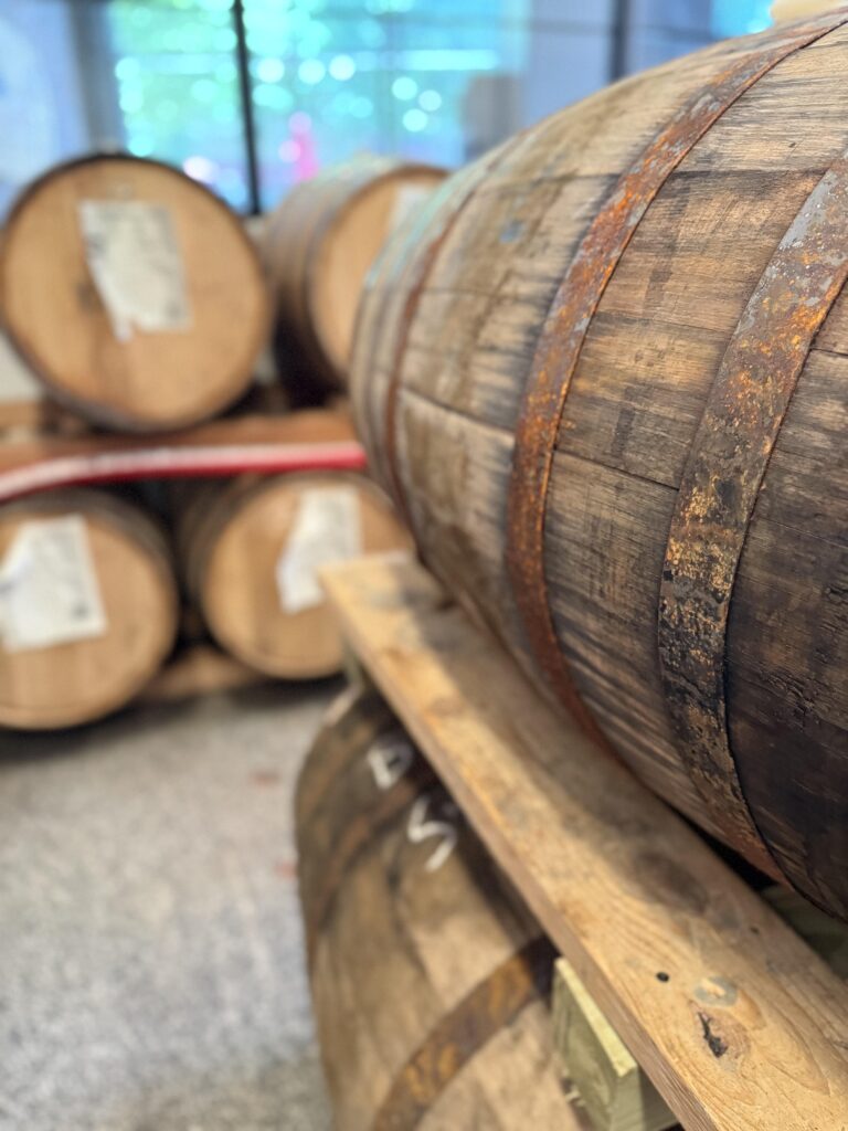 Whiskey barrels sitting in Open Road's busy distillation and blending room