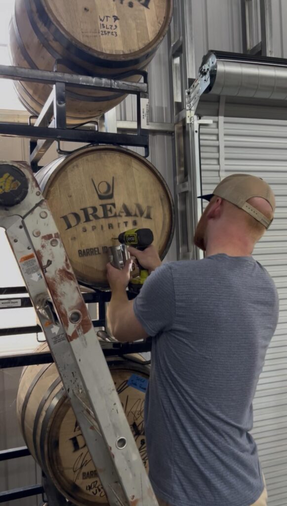 Ethan Pope drills into barrel to thieve whiskey at Dream Spirits