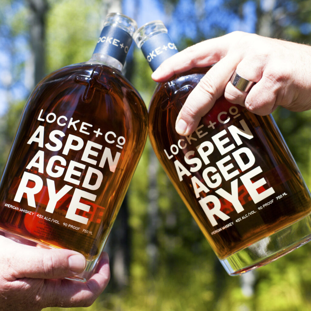 Locke + Co bottles cheersing near forest