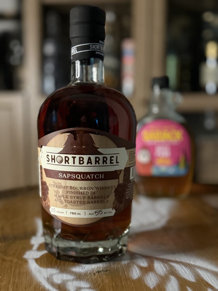 Shortbarrel Sapsquatch Maple-Finished Bourbon 2026 Release with maple syrup in background