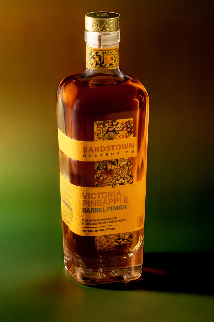 Bardstown Bourbon Company's new Victoria Pineapple Rum finished whiskey against yellow fading to green background