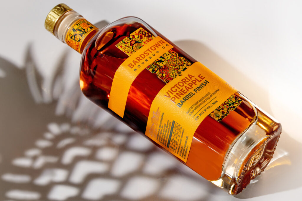 Bardstown Bourbon Company's new Victoria Pineapple Rum finished whiskey lies next to pineapple cutout shadow