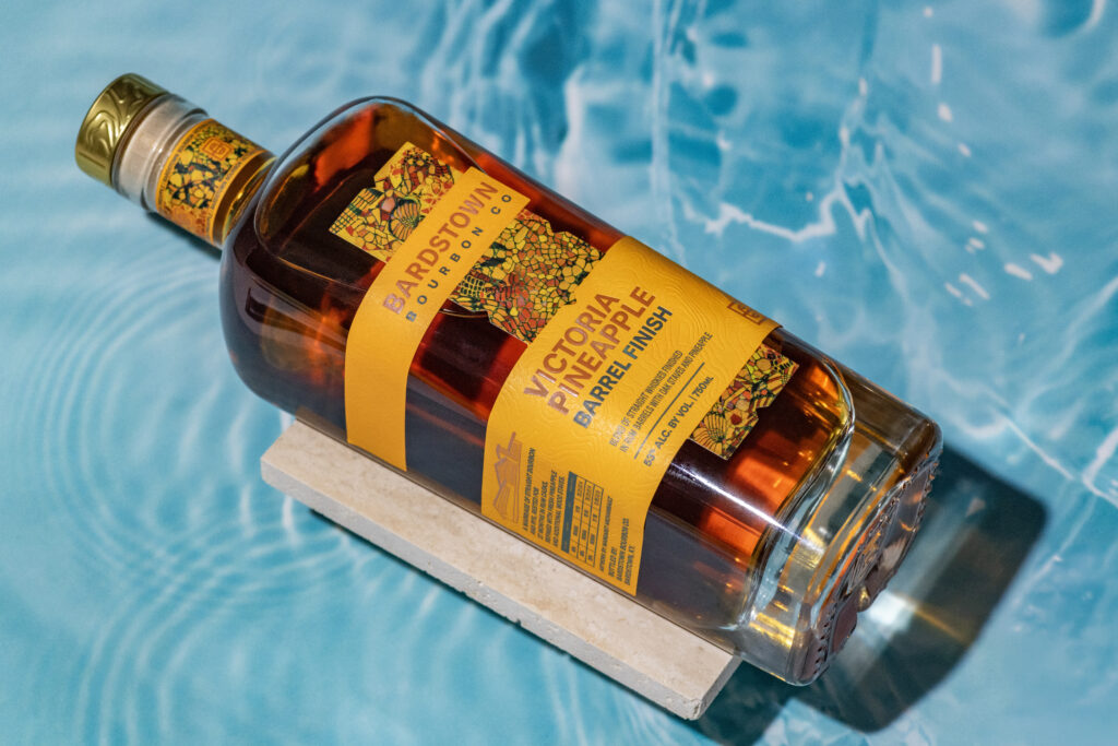 Bardstown Bourbon Company's new Victoria Pineapple Rum finished whiskey lies against water