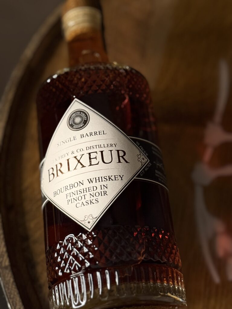Brixeur Spirits Triple Wine Finished Bourbon lying on whiskey barrel