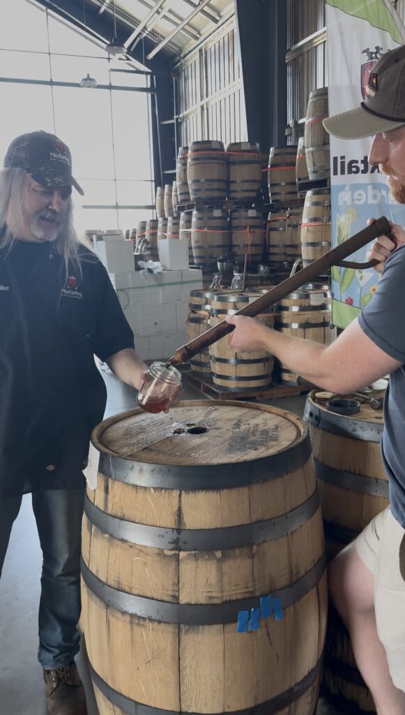 MurLarkey head distiller Kevin Szady holds glass as author Ethan Pope thieves straight from the barrel