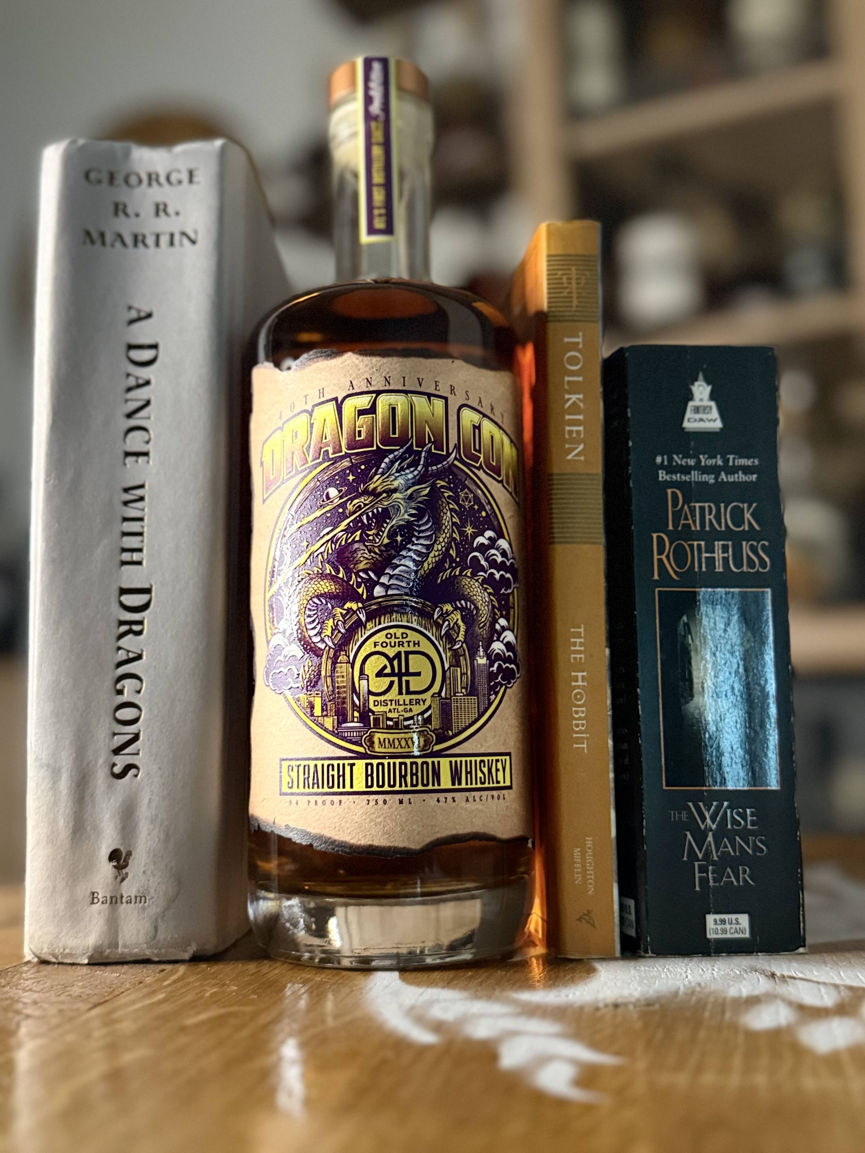 Old Fourth DragonCon 40th Anniversary Bourbon sandwiched between George RR Martin's "A Dance with Dragons", JRR Tolkien's "The Hobbit", and Patrick Rothfuss' "A Wise Man's Fear"
