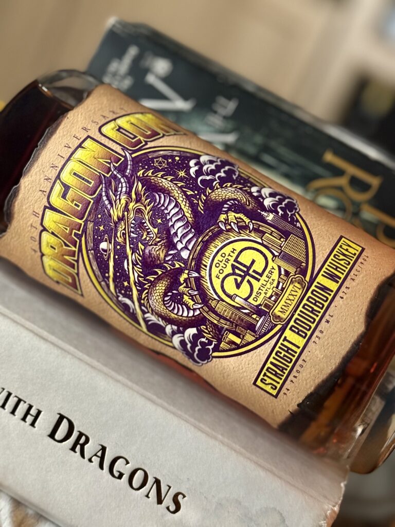 Old Fourth DragonCon 40th Anniversary Bourbon lies against George RR Martin's "A Dance with Dragons", JRR Tolkien's "The Hobbit", and Patrick Rothfuss' "A Wise Man's Fear"