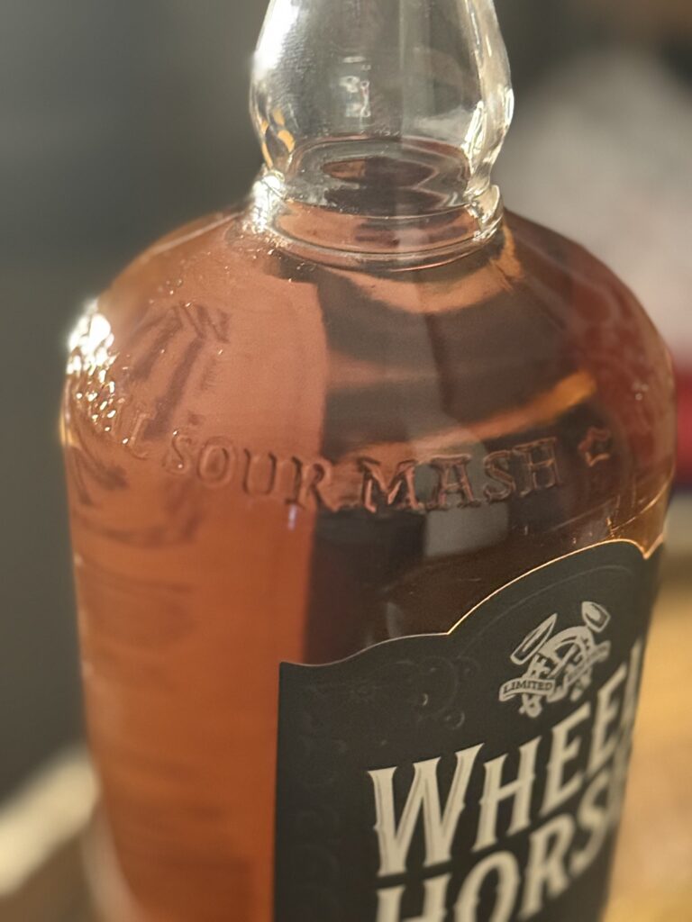 Wheel Horse's new 2026 release, a Double Mash Rum Finished Whiskey with the embossed glass "sour mash" glowing