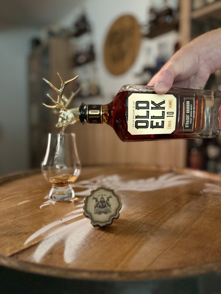 Old Elk 10-Year Bourbon pouring from golden elk head spout into glencairn
