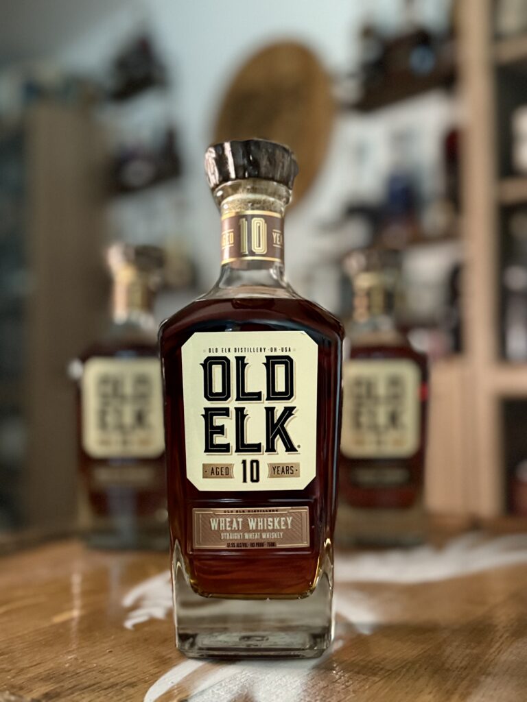 Old Elk 10-Year Wheat Whiskey with rest of collection blurred behind it