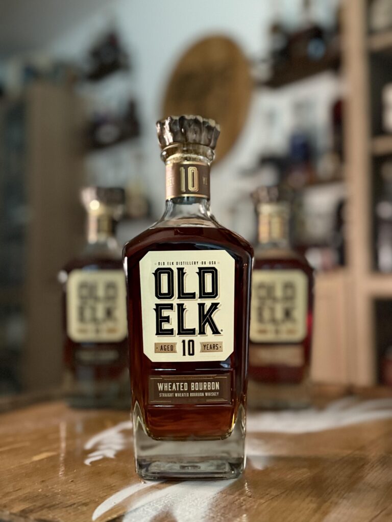 Old Elk 10-Year Wheated Bourbon with rest of collection blurred behind it