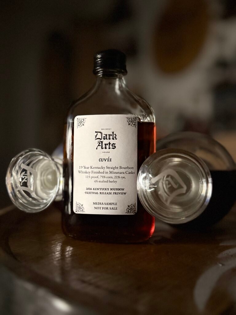 Dark Arts KBF Special Release: Chief Alchemist Reserve Cuvée 19 Year Kentucky Bourbon finished in Mizunara Casks stands between two Dark Arts bottle toppers