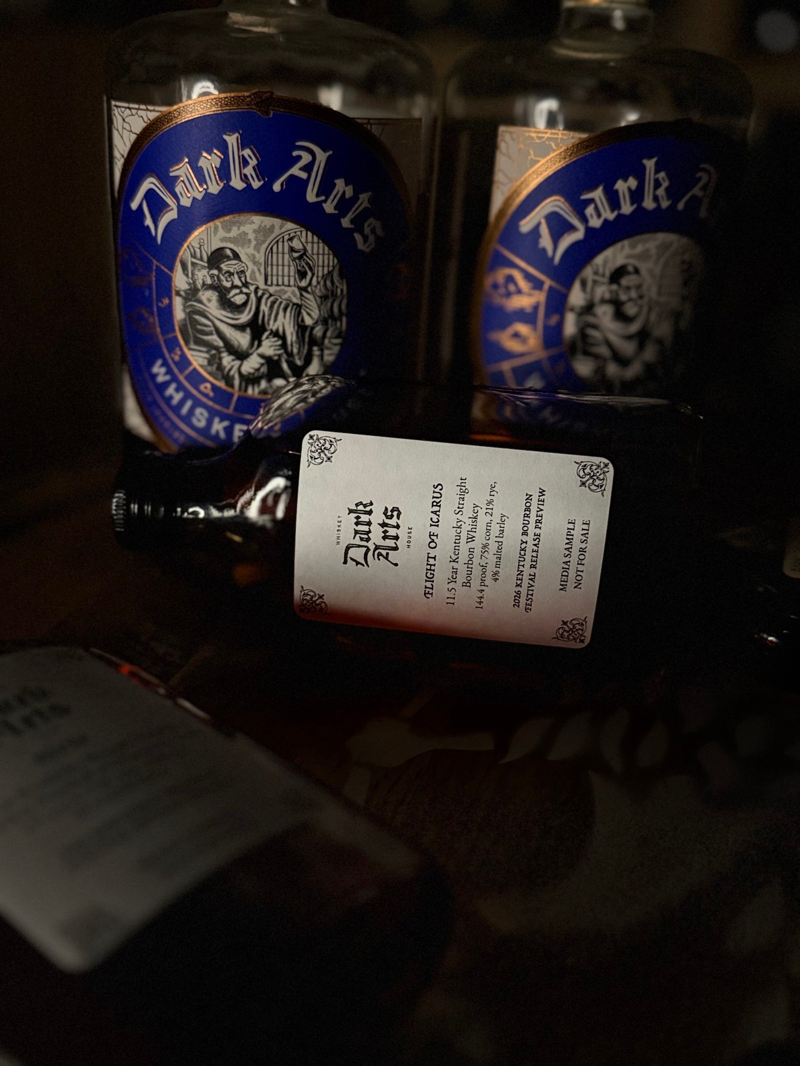 Dark Arts KBF Special Release: "Flight of Icarus" 11.5 Year Hazmat Kentucky Bourbon lies in front of past blue label releases