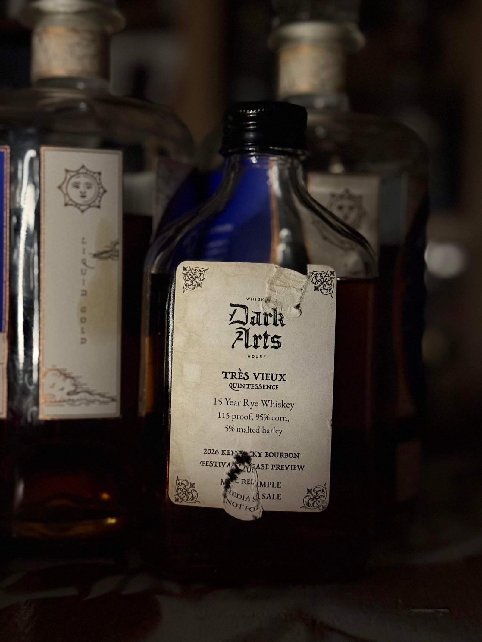 Dark Arts KBF Special Release: "Tres Vieux" 15 Year Rye beside "liquid gold" label on each Dark Arts bottle