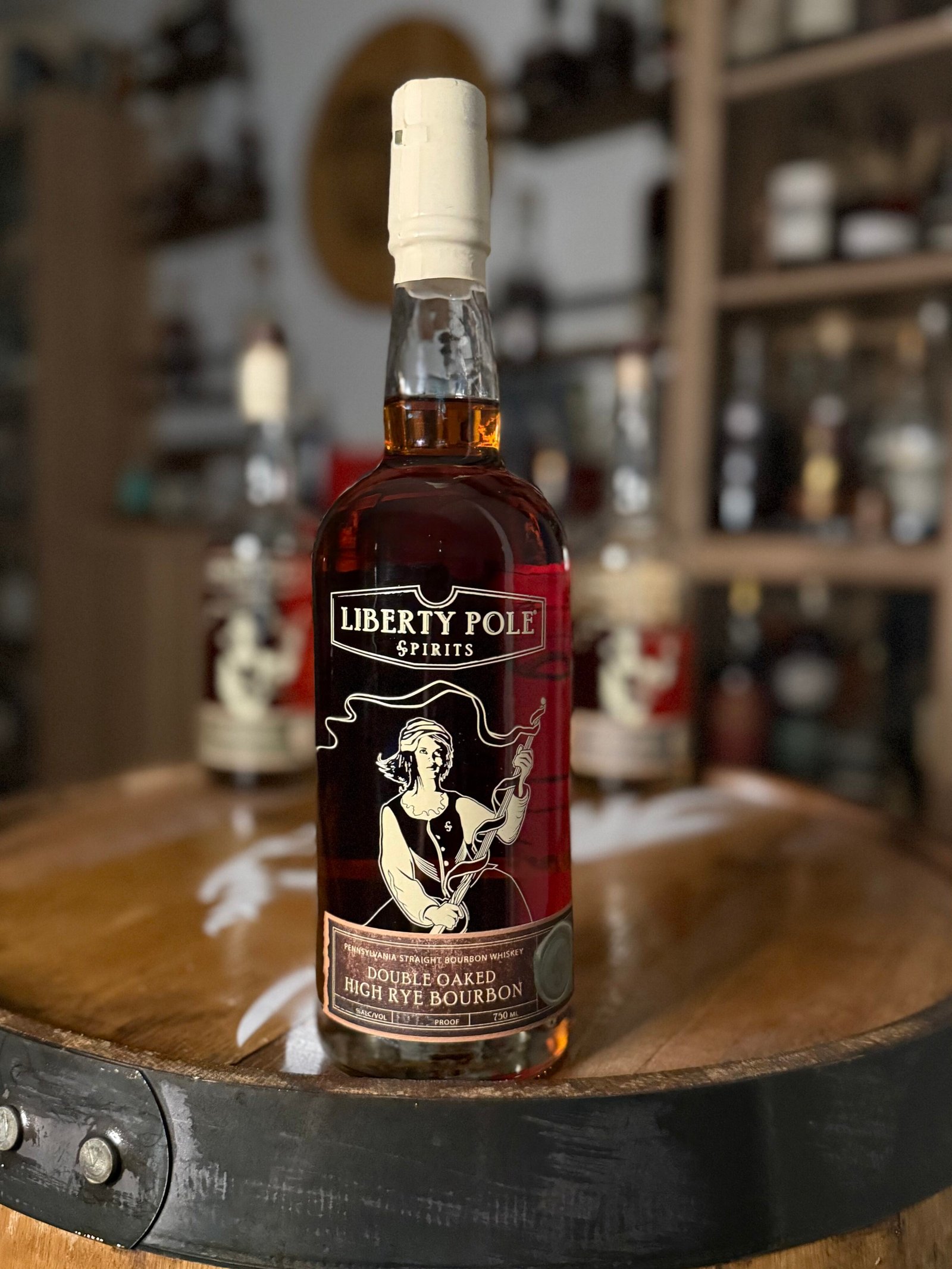 Liberty Pole Double Oaked High Rye Bourbon positioned in front of blurred past Liberty Pole releases