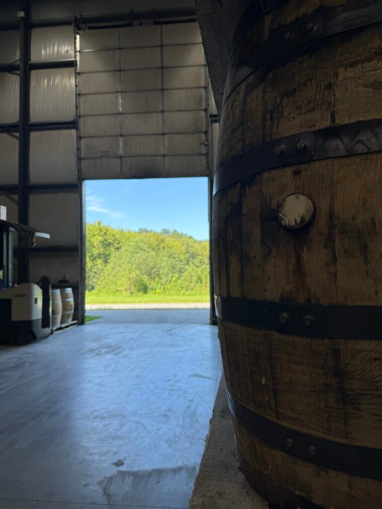 Green trees and rolling hills glisten with sunshine from inside the cask house