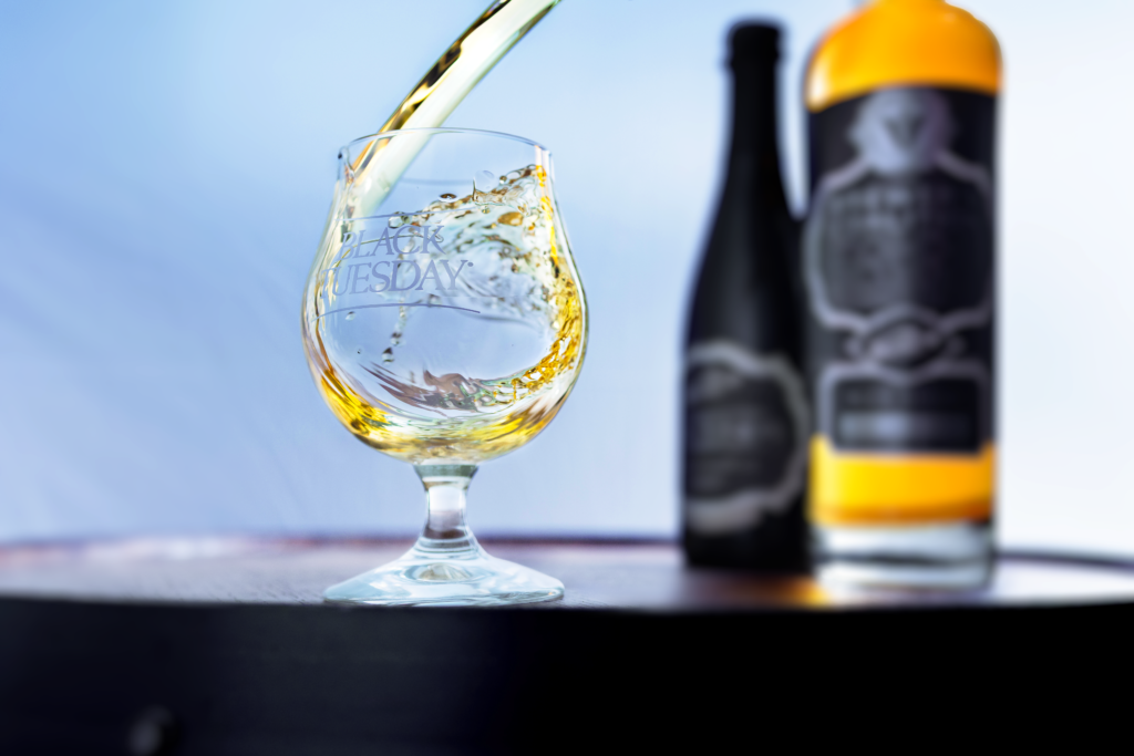 Virginia Distillery Co's newest Brewer's Coalition American single malt collaboration finished with The Bruery's Black Tuesday stout blurred beside the whiskey splashing into a Black Tuesday glass