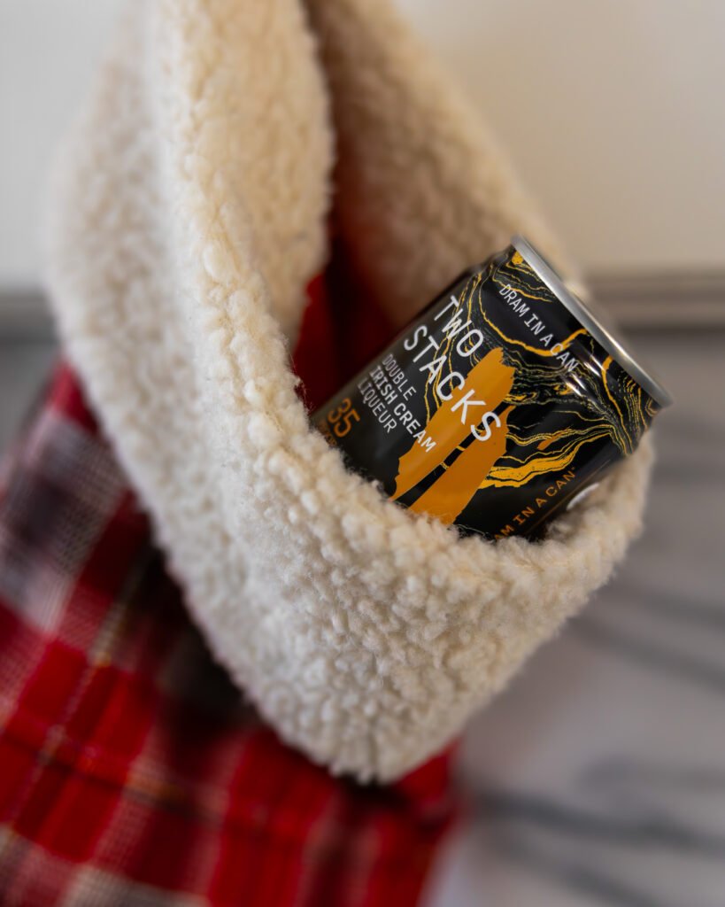 Two Stacks Double Irish Cream Liqueur Dram in a Can pokes out of the top of a holiday stocking