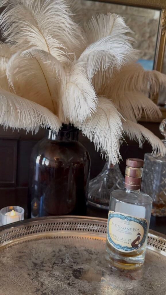 Mahogany Fox single barrel sits on tray against feather decoration