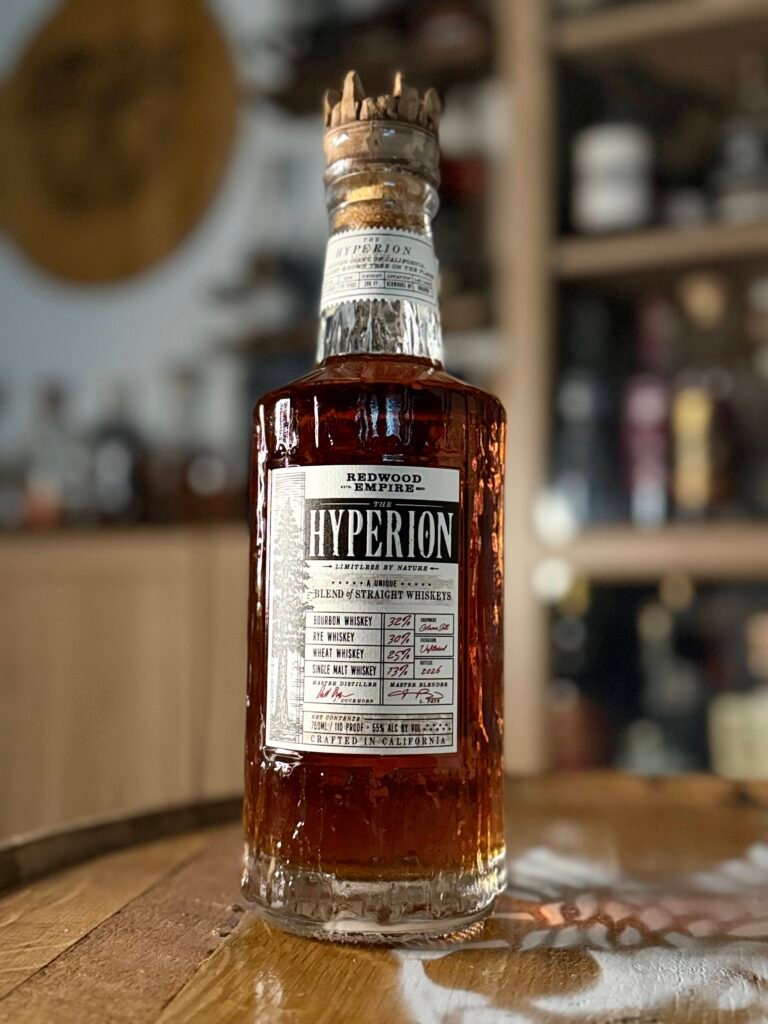 Redwood Empire The Hyperion whiskey sits on whiskey barrel in front of whiskey collection