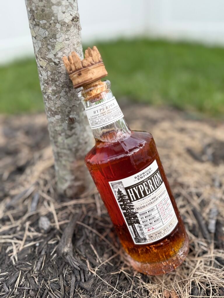 Redwood Empire The Hyperion whiskey leans against a thin tree trunk