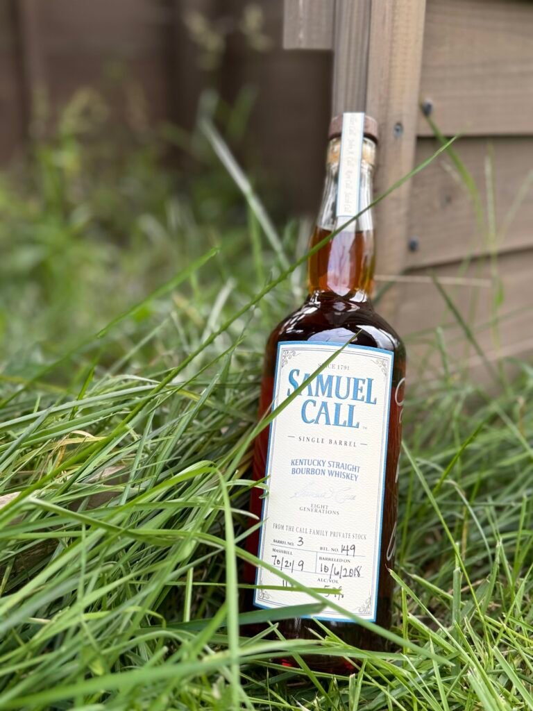 Samuel Call Barrel 3 lies in overgrown grass against wooden wall