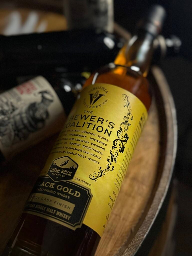 Brighter close-up of Virgina Distilling Co's Brewer Coalition "Black Gold" stout finished American single malt lying with darkened stouts behind it