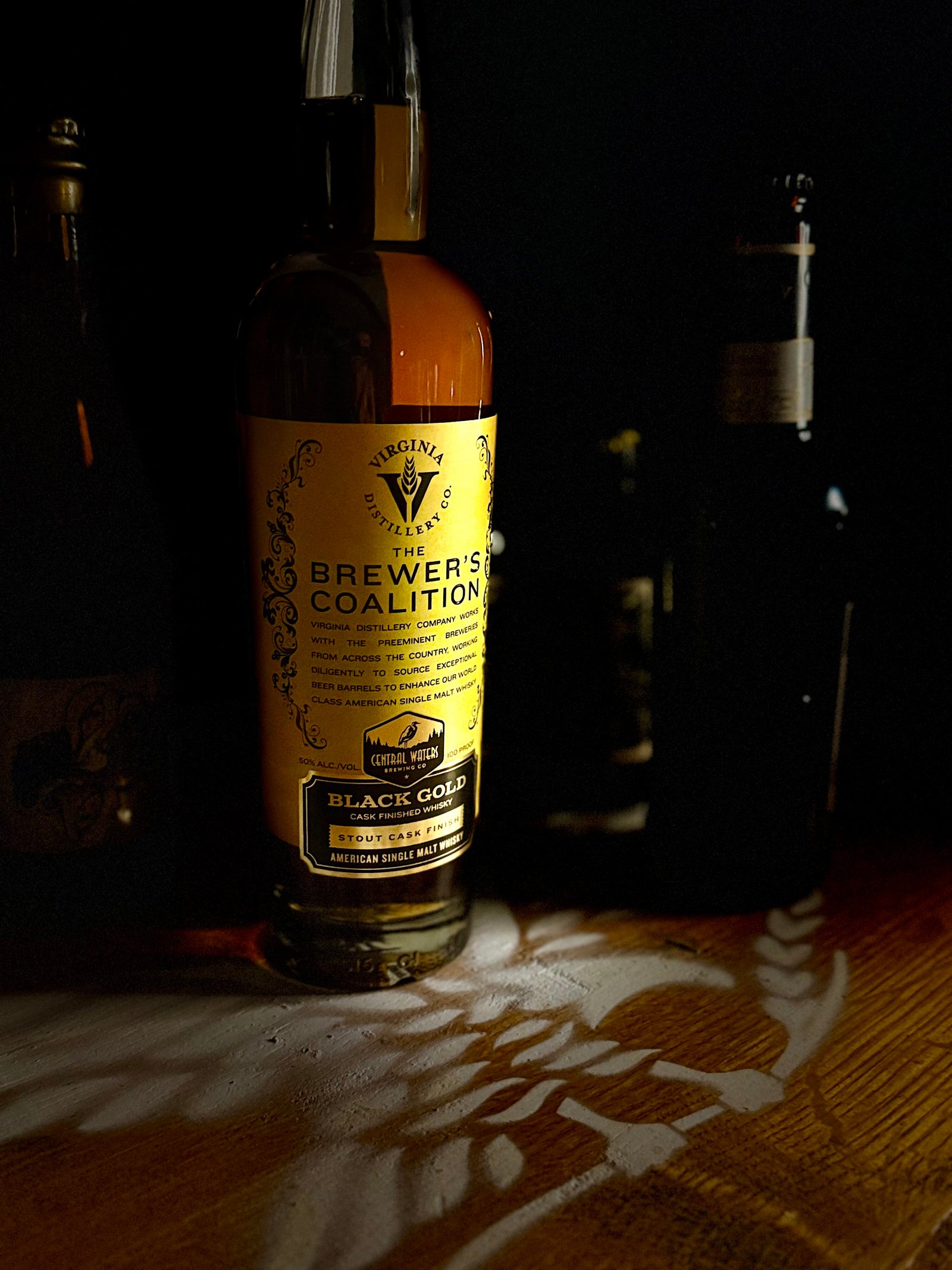 Virgina Distilling Co's Brewer Coalition "Black Gold" stout finished American single malt stands with darkened stouts behind it