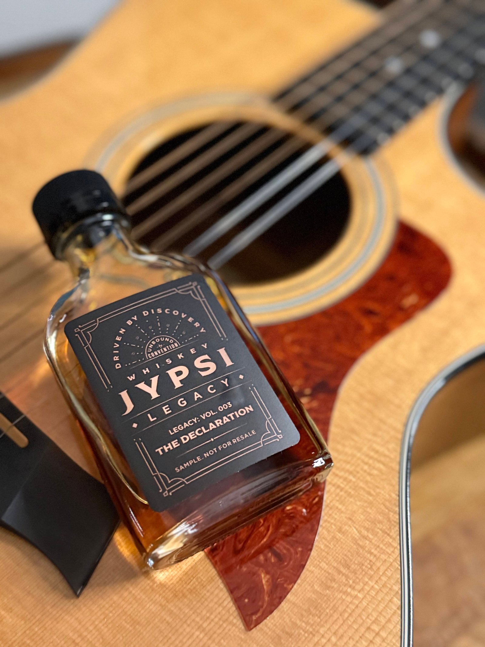 Whiskey JYPSI Legacy Batch 003 "The Declaration" lies across face of guitar