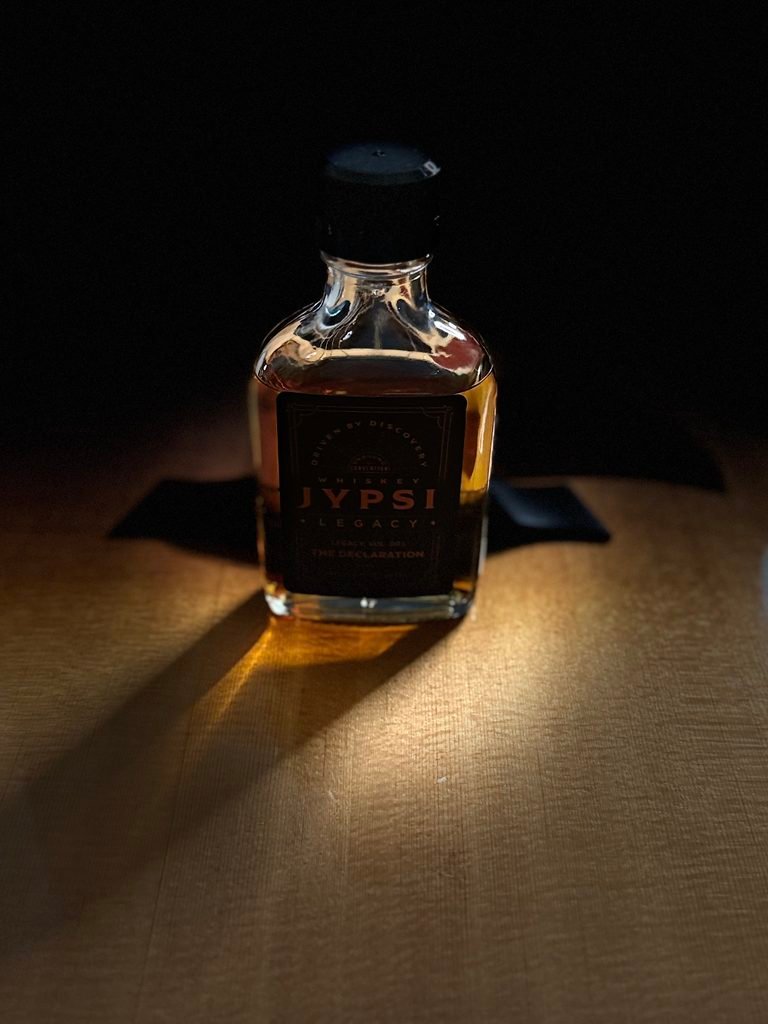 Whiskey JYPSI Legacy Batch 003 "The Declaration" darked with light streaming through as it stands on guitar face